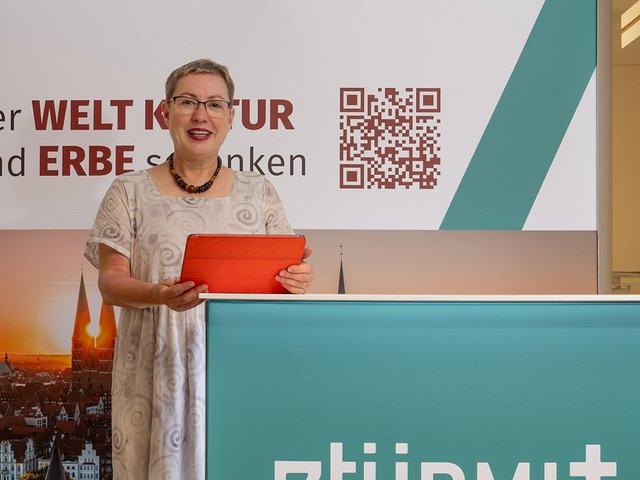 Die Lübecker Pröpstin Petra Kallies präsentiert den neuen Messestand der Stiftung 7Türme+